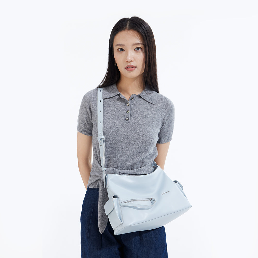 Woman in grey polo shirt modeling light blue crossbody bag, Amazing Song official website