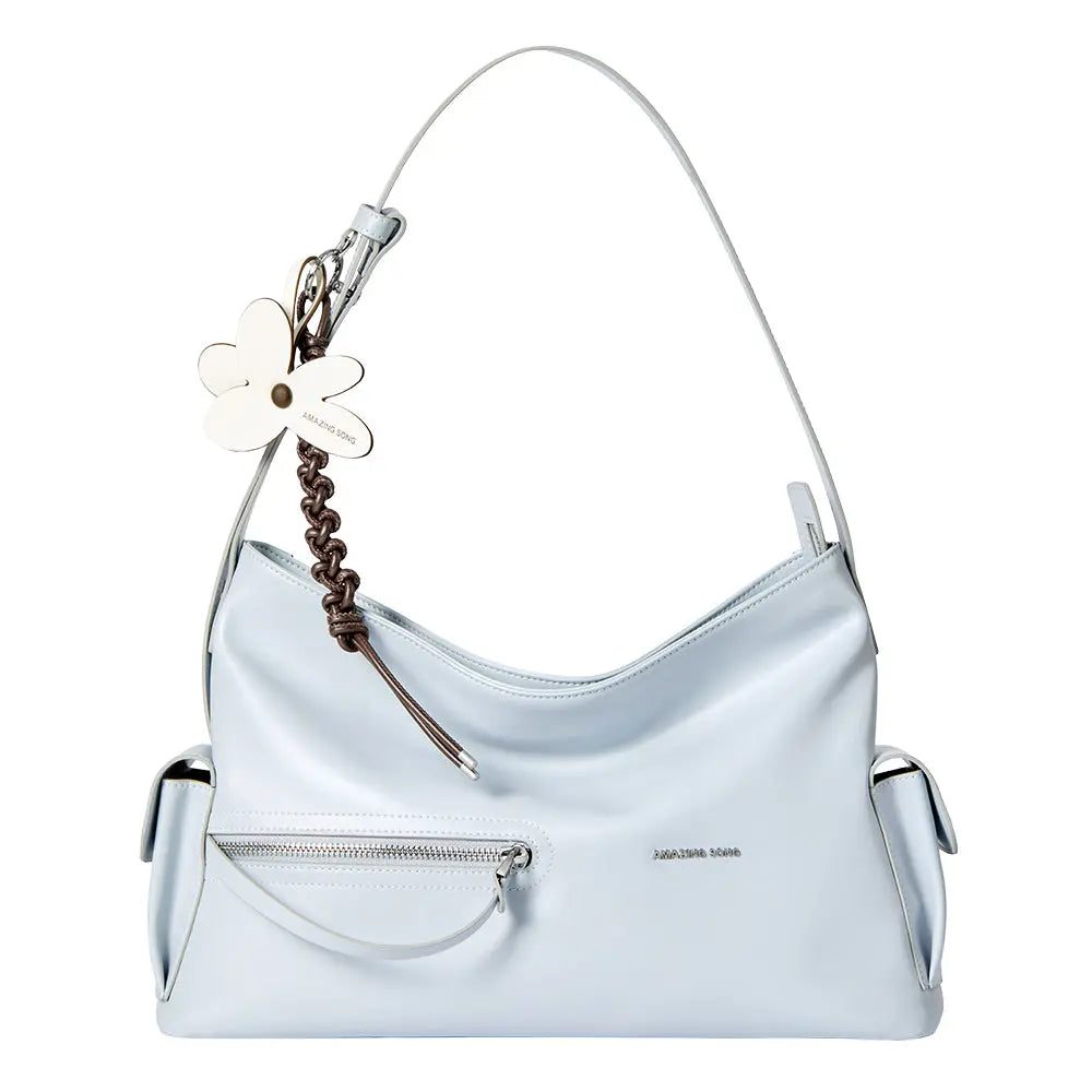 Light blue Amazing Song handbag with front zipper pocket and flower keychain on white background