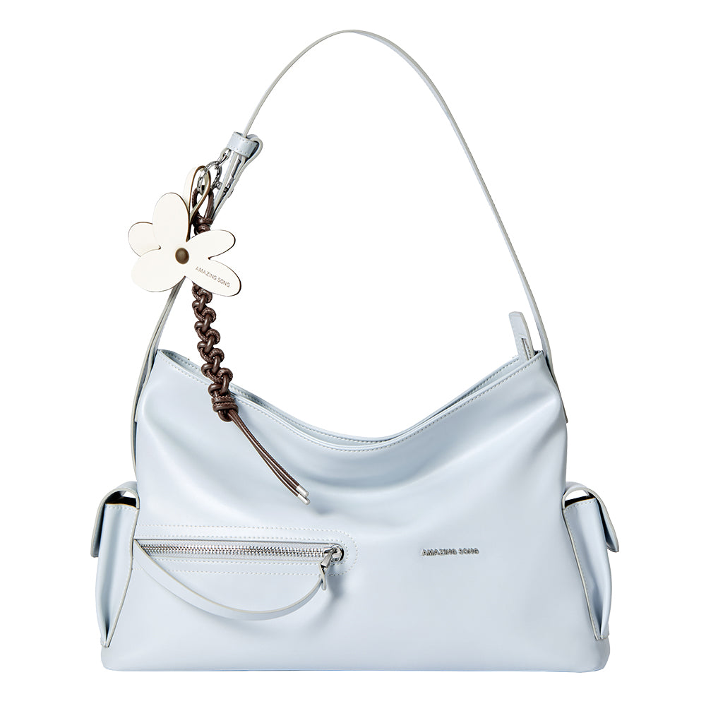 Light blue Amazing Song handbag with front zipper pocket and flower keychain on white background