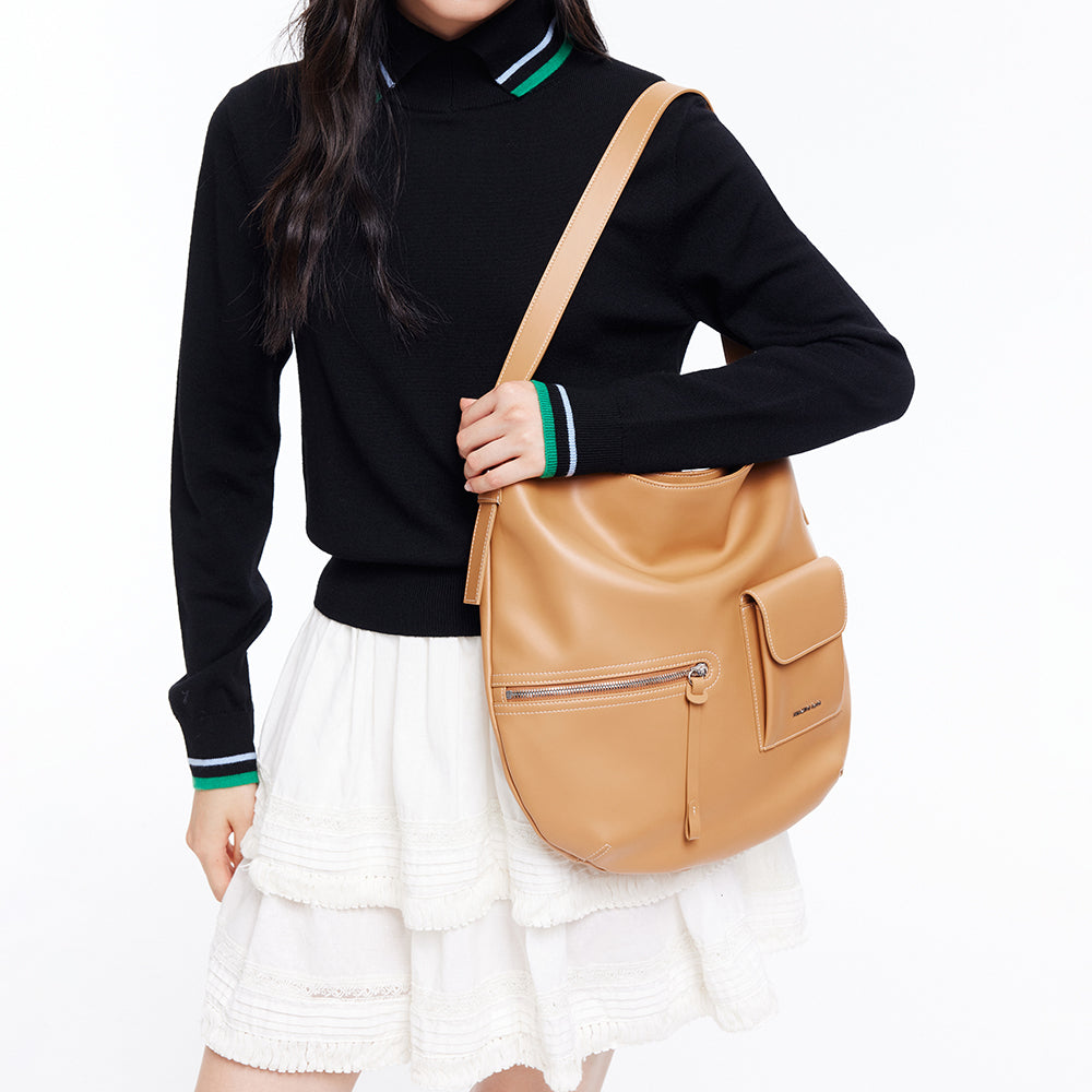 Woman wearing black sweater, white skirt, and tan leather shoulder bag, Amazing Song