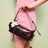 Woman holding dark brown Amazing Song handbag with flower charm, wearing pink dress