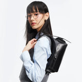 Stylish woman with glasses wearing a grey vest and blue shirt carrying a black handbag