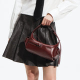 Woman in white blouse and black skirt holding a burgundy leather Amazing Song handbag