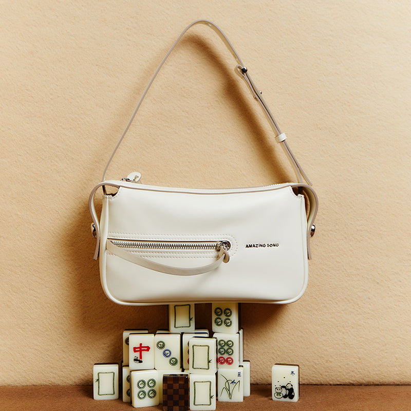 Amazing Song white leather shoulder bag with zipper, displayed on mahjong tiles