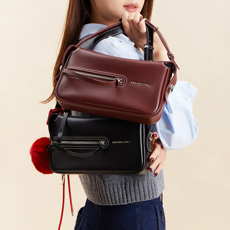 Woman holding Amazing Song handbags in burgundy and black with stylish zip details