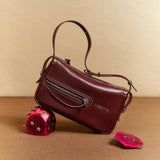 Amazing Song burgundy leather handbag with zipper detail, styled with dragon fruit on beige background