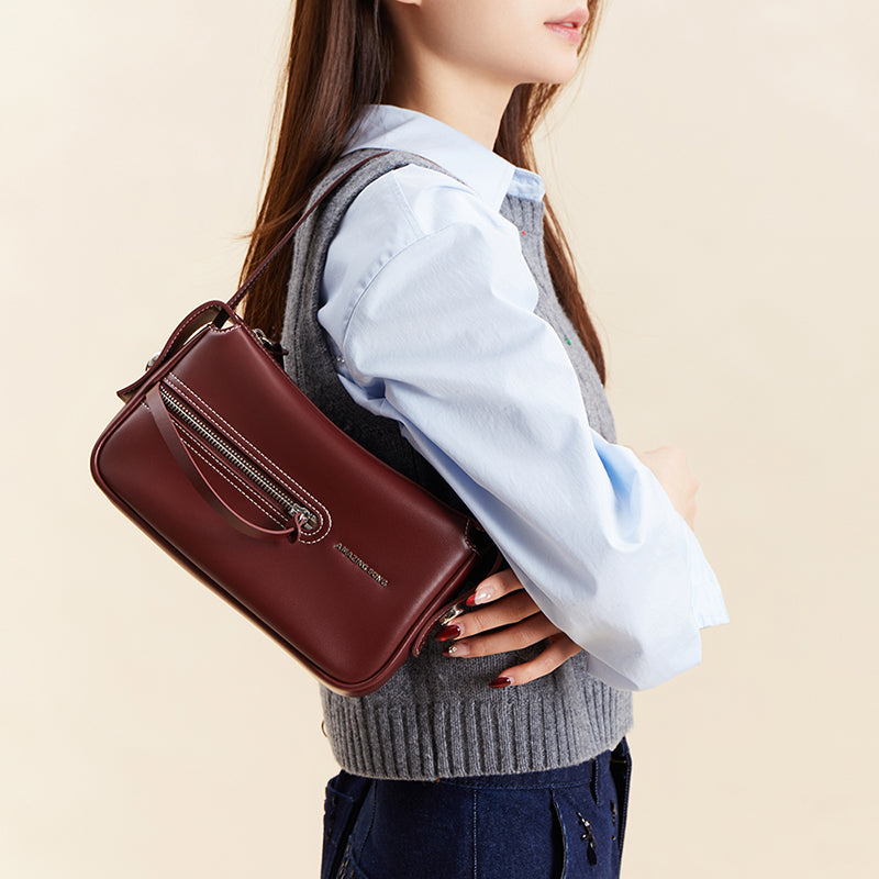 Woman with burgundy shoulder bag, blue shirt, and grey vest, Amazing Song official website