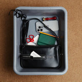 Amazing Song black handbag in tray with glasses, phone, notebook, and accessories