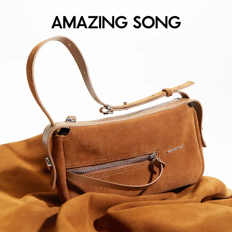 Amazing Song brown suede shoulder bag with zipper, displayed on matching fabric