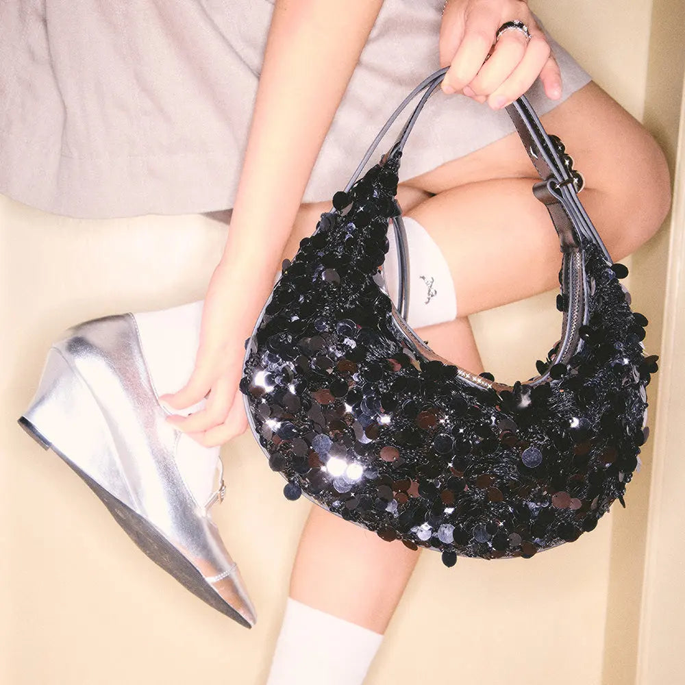 Woman holding black sequin handbag and wearing silver wedge heels, Amazing Song fashion