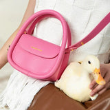 Amazing Song pink handbag with gold logo, held by person in knit top and pet duck