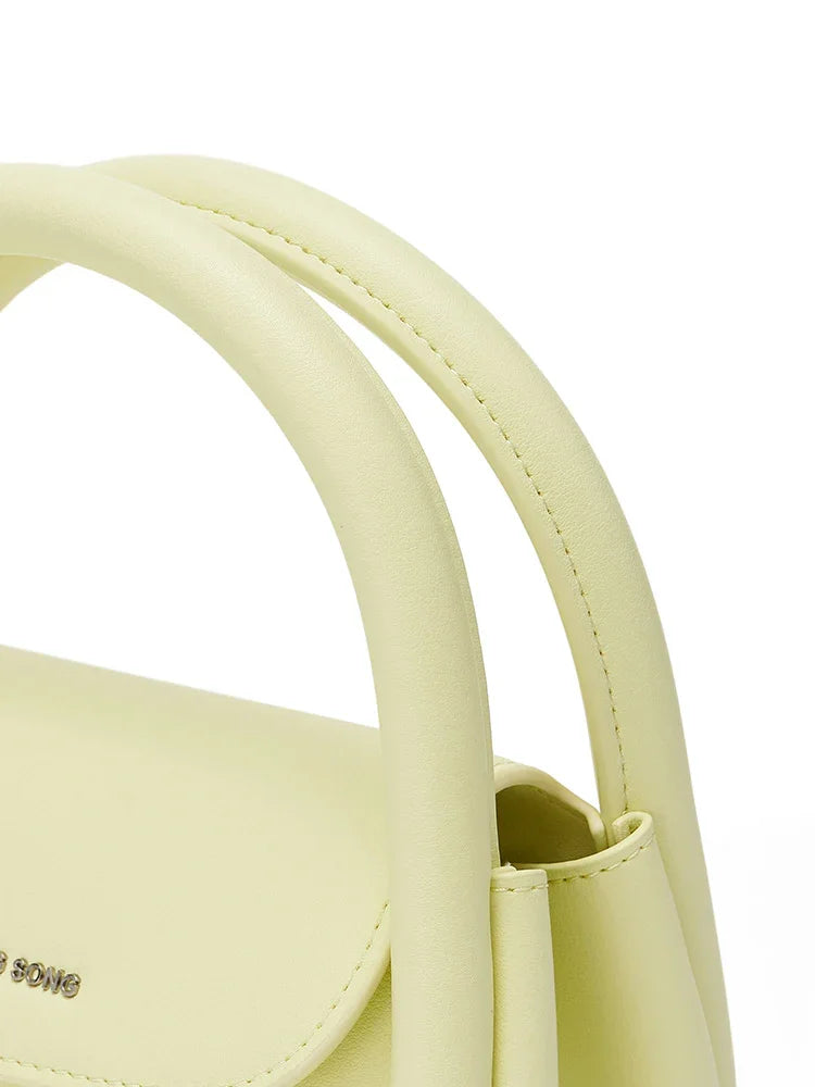 Close-up of pale yellow Amazing Song handbag with curved handles and logo detail