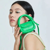 Model holding bright green Amazing Song mini handbag with gold logo, stylish fashion accessory