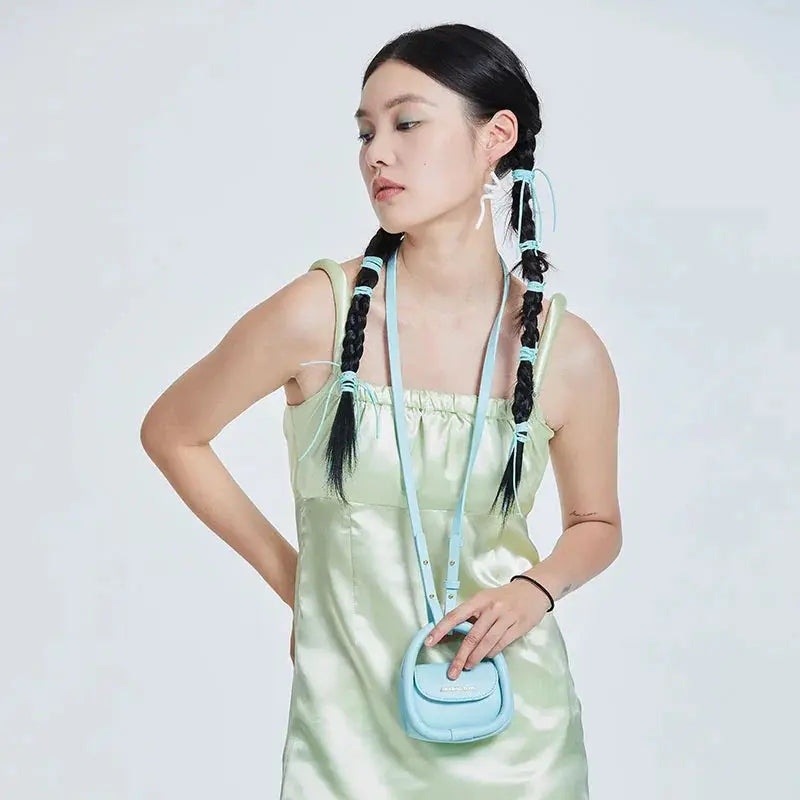 Woman in pastel green satin dress with braids and blue mini bag, Amazing Song fashion