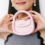 Woman holding a small pink Amazing Song handbag, smiling, against a white background.