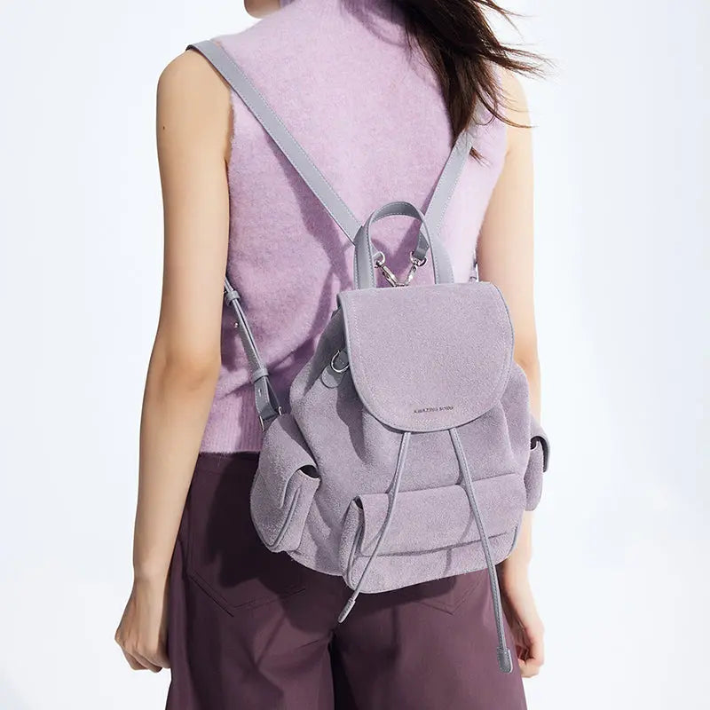 Woman wearing a light purple Amazing Song backpack with lavender top and dark pants