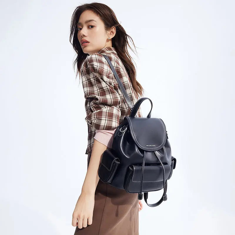 Woman in plaid shirt modeling black Amazing Song backpack against white background