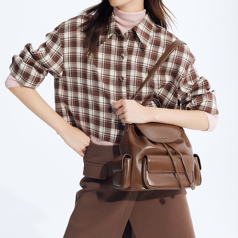 Woman in plaid shirt and brown skirt holding stylish brown leather backpack, Amazing Song