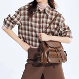 Woman in plaid shirt and brown skirt holding stylish brown leather backpack, Amazing Song