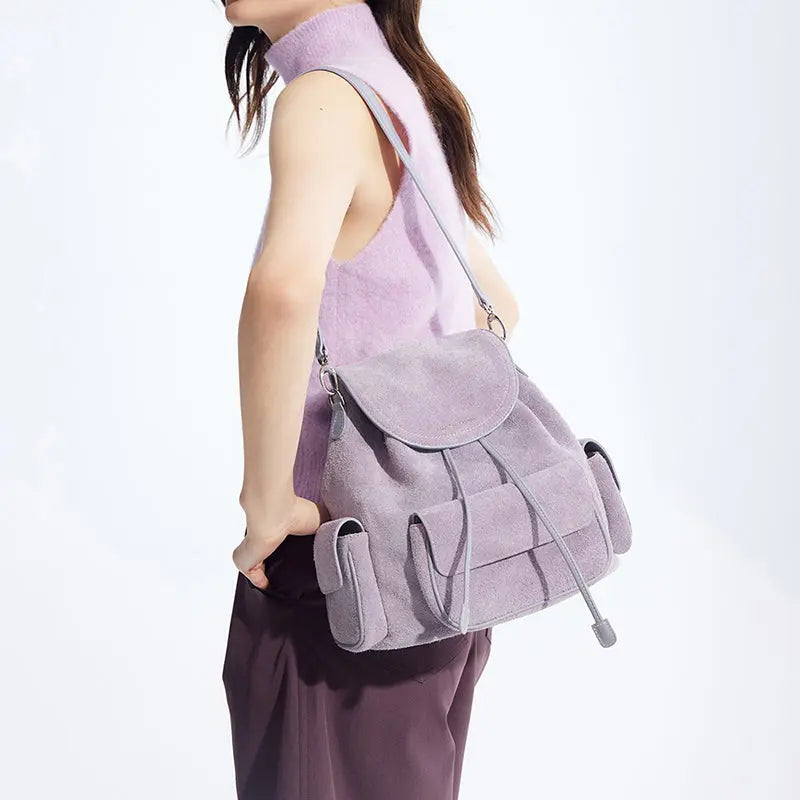 Woman in sleeveless lilac top modeling a light purple suede backpack, Amazing Song official site