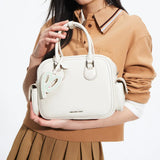 Woman holding Amazing Song cream handbag with heart tag, stylish fashion accessory