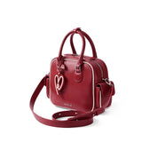 Amazing Song red leather handbag with heart keychain and shoulder strap on white background