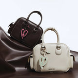 Amazing Song handbags in brown and cream with heart charms on brown fabric backdrop
