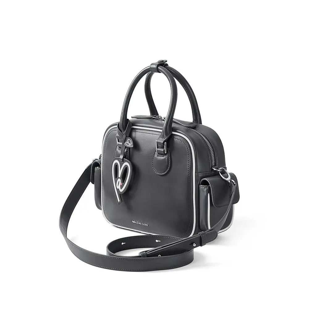 Amazing Song black leather handbag with heart keychain, top handles, and shoulder strap