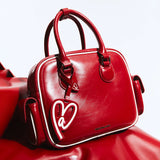 Amazing Song red leather handbag with white trim and heart tag on white background