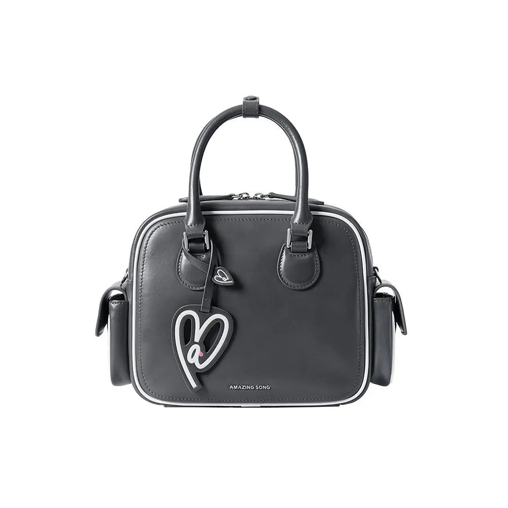 Amazing Song black leather handbag with heart keychain, top handles, and side pockets