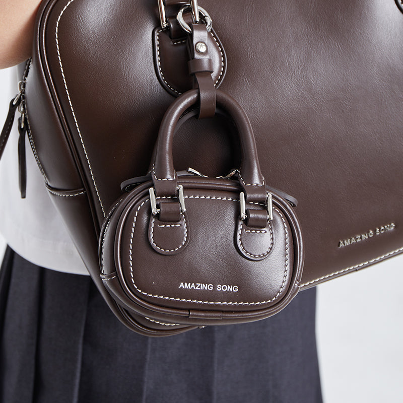 Amazing Song brown leather mini bag with white stitching attached to larger matching bag