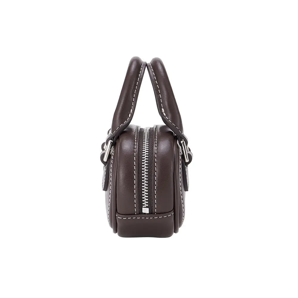 Side view of a brown leather handbag with white stitching and a zipper, Amazing Song