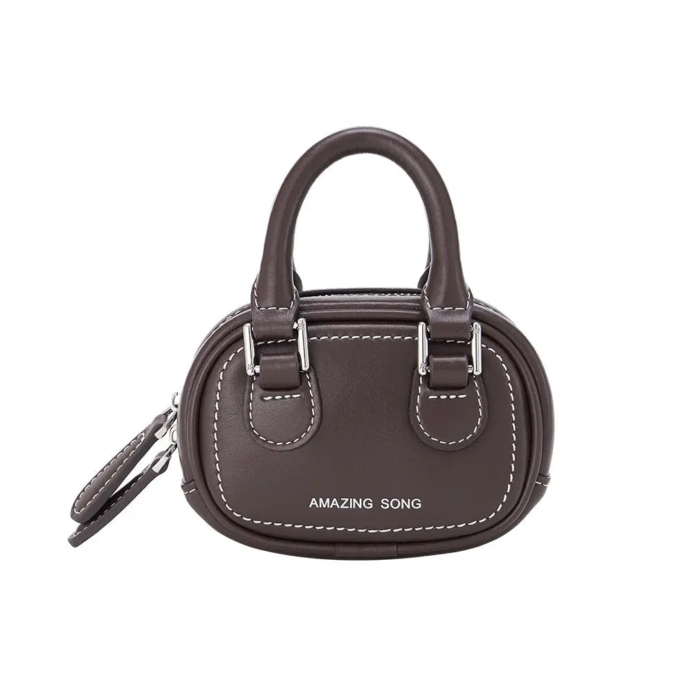 Amazing Song brown mini handbag with dual handles and white stitching, studio background