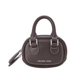 Amazing Song brown mini handbag with dual handles and white stitching, studio background