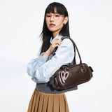 Woman wearing glasses with a brown shoulder bag featuring pink heart detail from Amazing Song