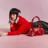 Woman in red sweater with red Amazing Song handbag on pink background