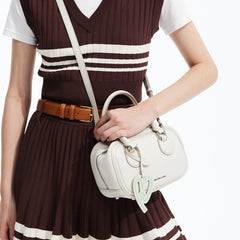 Woman in brown dress holding a white Amazing Song handbag with heart keychain