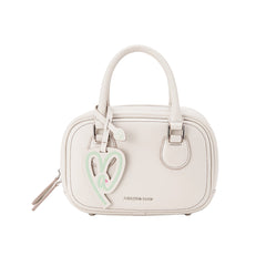 Amazing Song beige handbag with heart charm and twin handles on white background