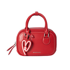 Amazing Song red handbag with heart charm and top handles on white background