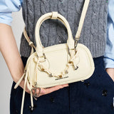 Amazing Song cream handbag with heart charm, crossbody style, held by person in grey vest