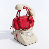 Amazing Song red handbag on vintage beige rotary phone white background