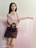 Young woman in pink top and brown skirt holding black handbag, Amazing Song brand promo