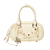 Cream Amazing Song handbag with decorative charms and dual handles on white background