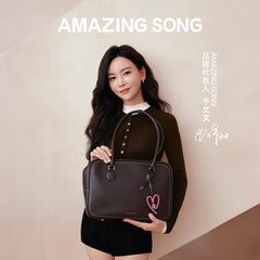 Woman modeling dark brown Amazing Song handbag with heart charm on official website banner