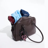 Brown leather handbag with blue sweater, pink heart charm, Amazing Song branding