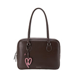 Amazing Song brown leather handbag with double handles and pink heart charm on white background