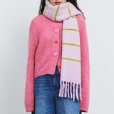 Woman wearing a pink sweater with pink buttons and fringe lilac scarf, Amazing Song fashion