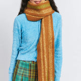Woman in blue sweater, plaid skirt, and brown striped scarf, Amazing Song fashion