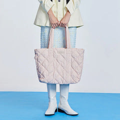 Woman holding a large quilted pastel pink tote bag, white boots, blue skirt, Amazing Song