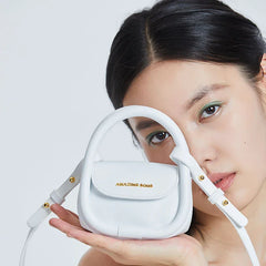 Woman holding white Amazing Song mini handbag close to her face, minimalist style